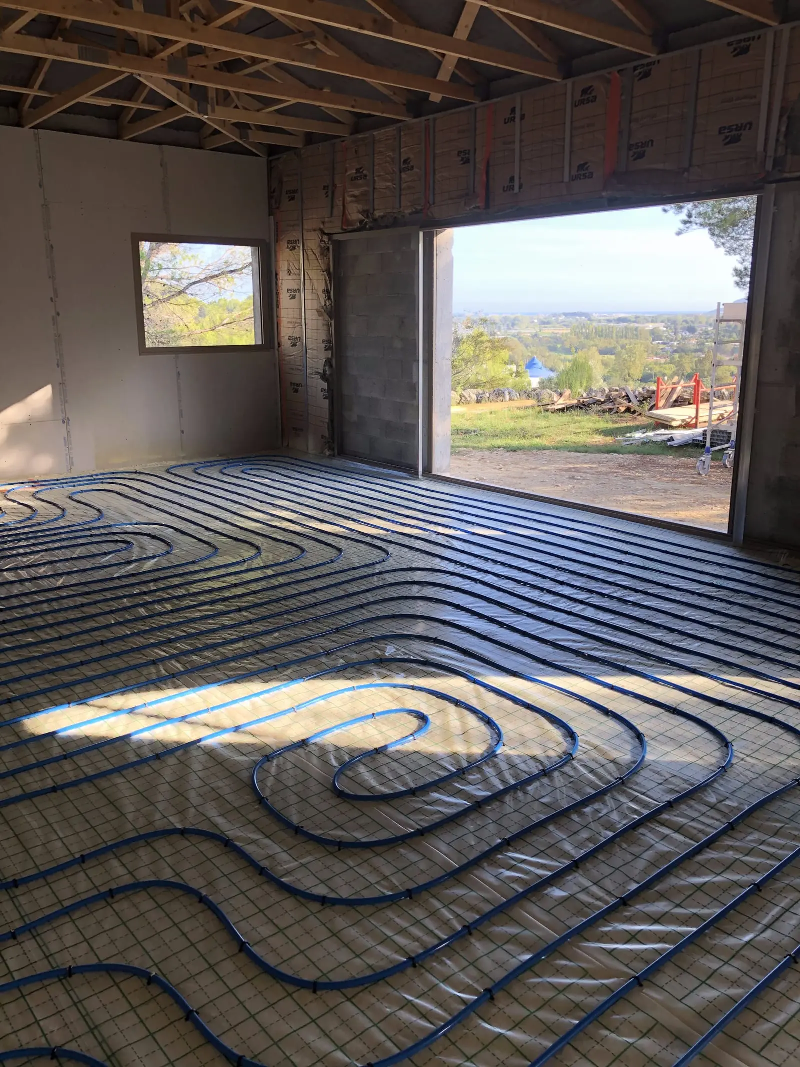 Plancher chauffant posé sur isolant thermique dans une maison en rénovation avec vue sur la vallée