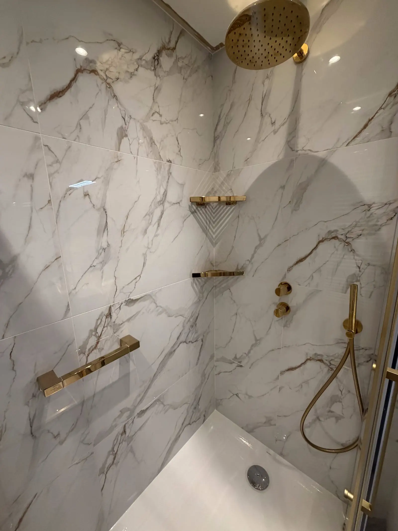 Douche effet marbre avec robinetterie dorée et pommeau de pluie haut de gamme posée par CMVR