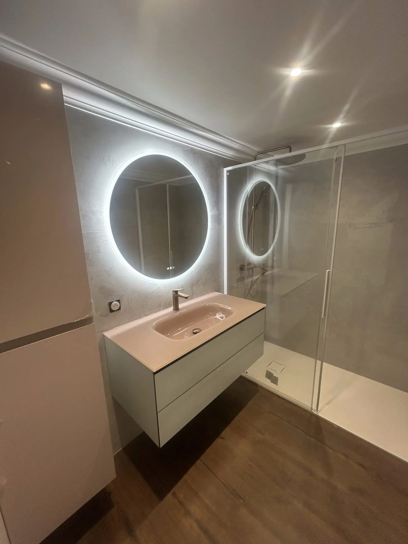Salle de bain rénovée avec vasque suspendue, miroir rond rétroéclairé et douche à l'italienne par CMVR