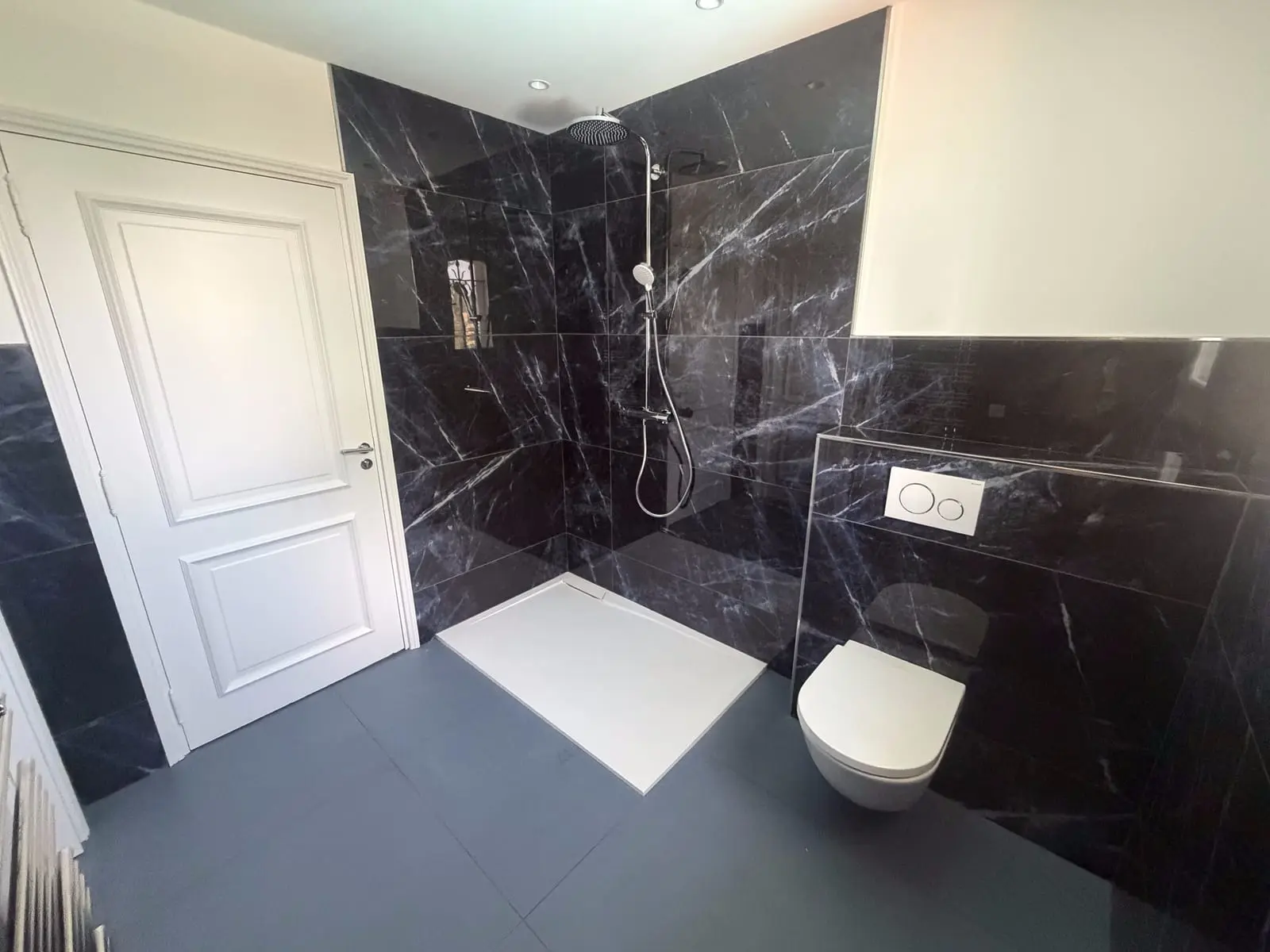 Salle de bain rénovée en marbre noir par CMVR avec ses partenaires carreleurs